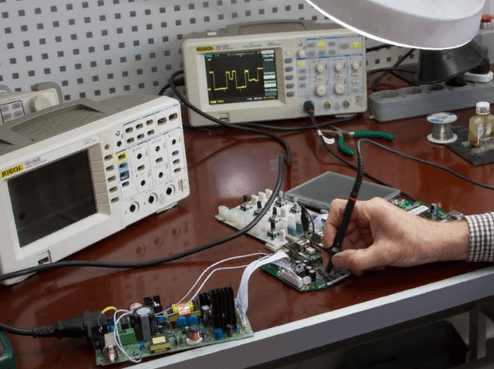Ремонт оборудования видеонаблюдения Измерительные приборы на рабочем столе, инженер ремонтирует плату видеозахвата