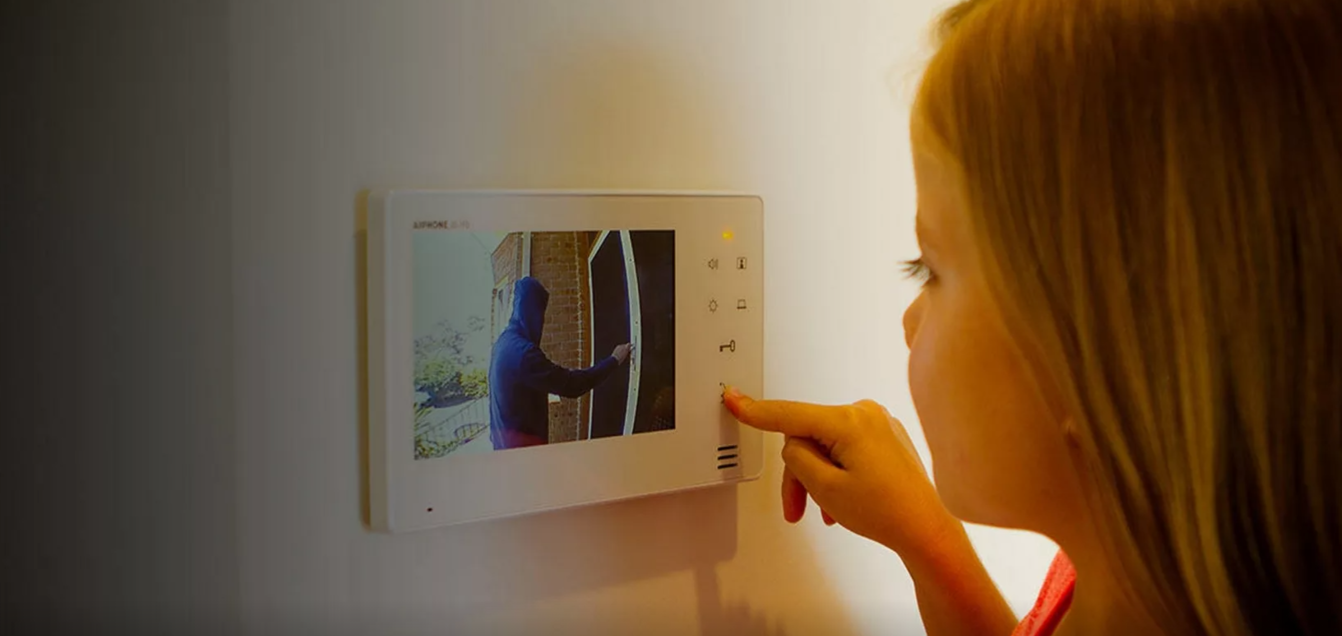 Девочка нажимает на кнопку открытия на мониторе видеодомофона