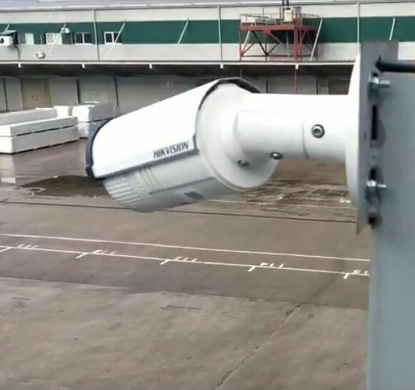 Уличная видеокамера на самодельном кронштейне направлена на здание предприятия